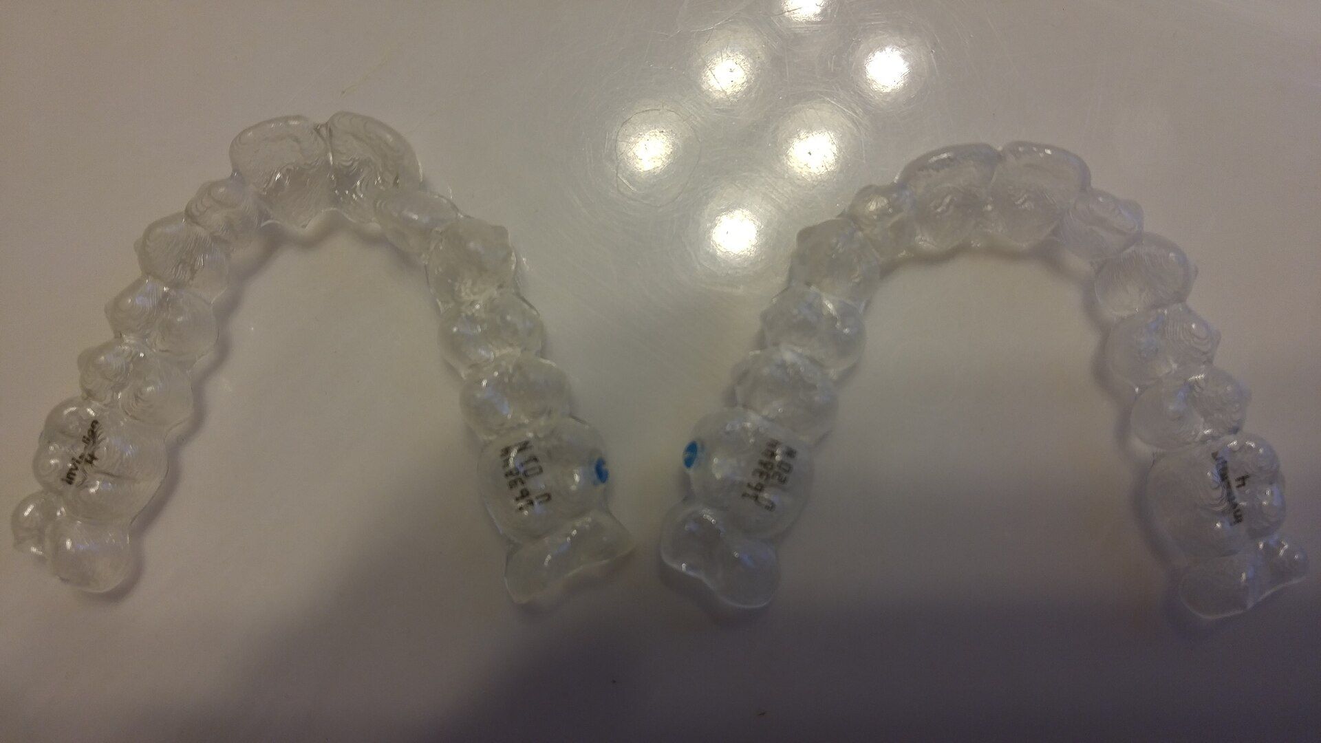 Dos alineadores dentales transparentes sobre una superficie clara.